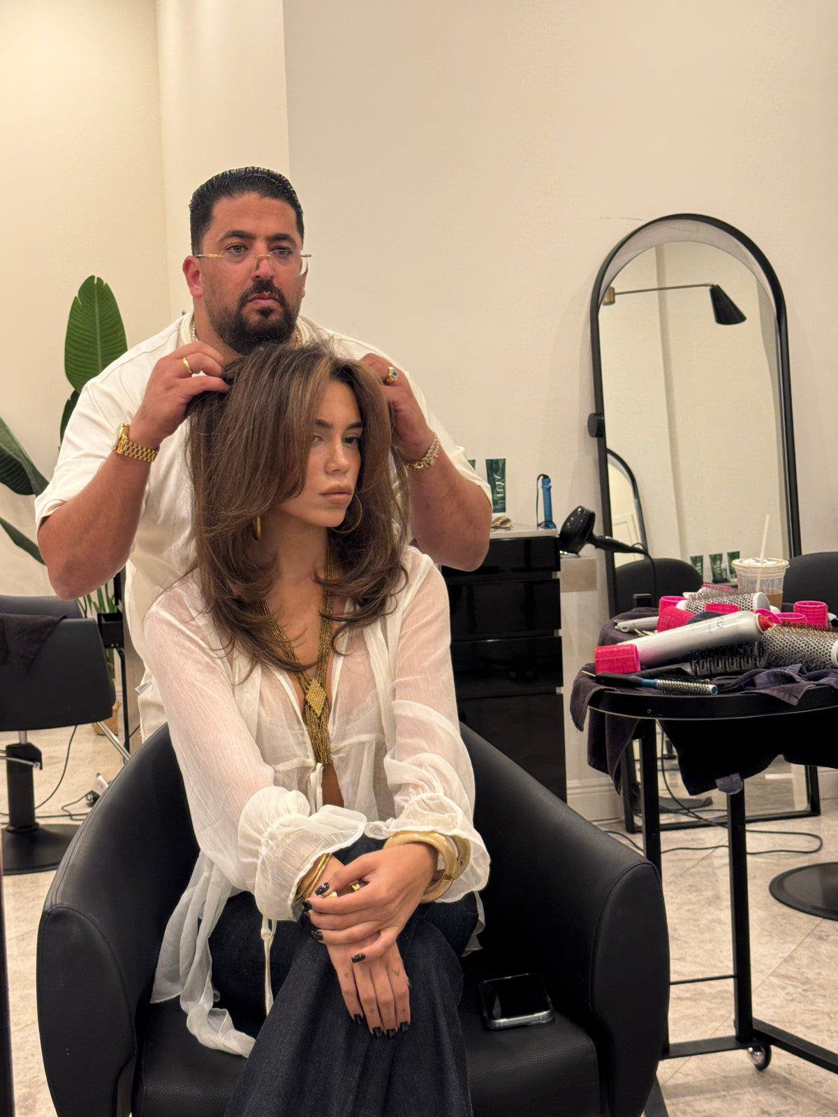 Shak working on a seated client's long brown hair