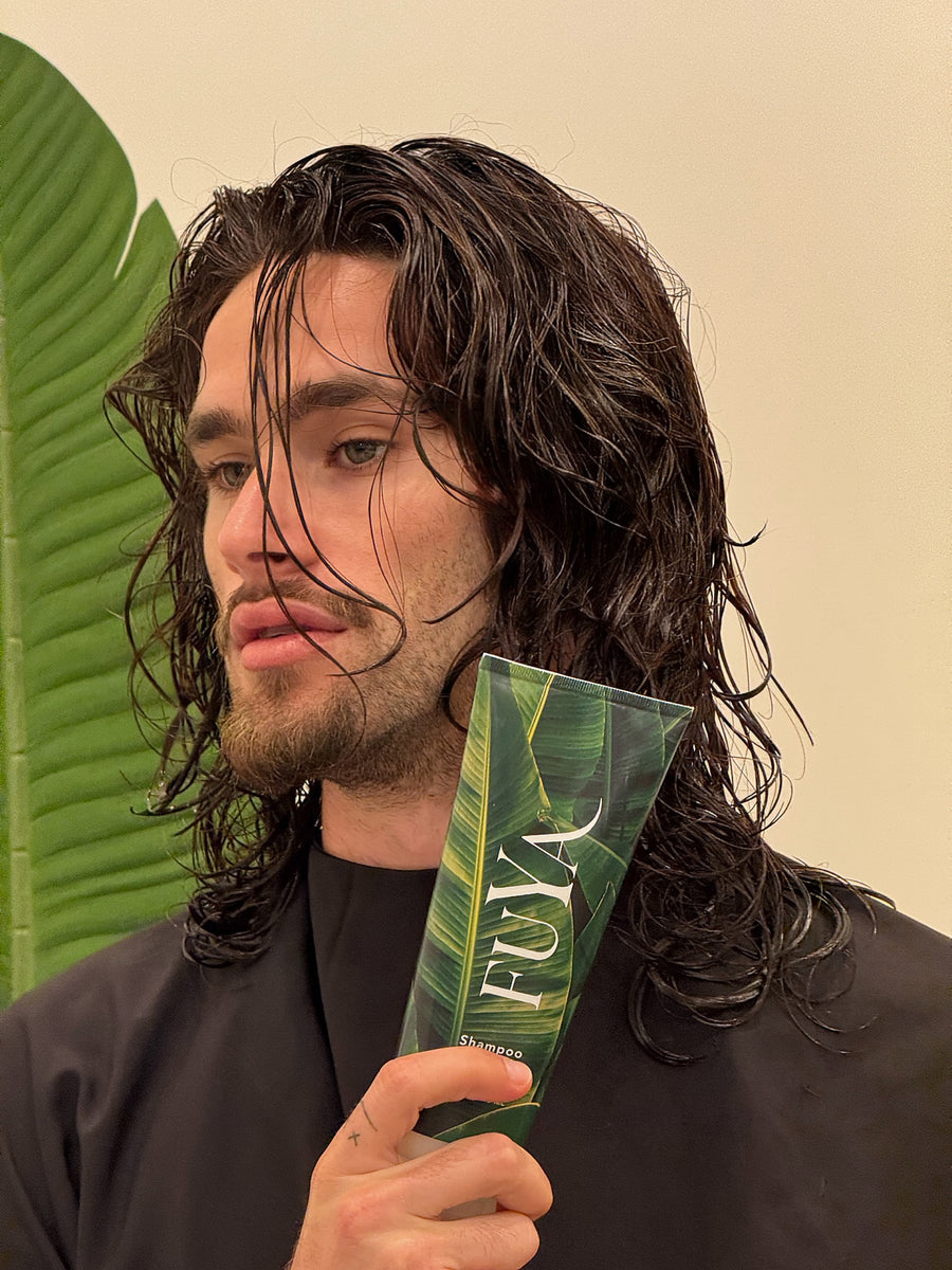 Man with shoulder-length curly hair holding a FUYA bottle